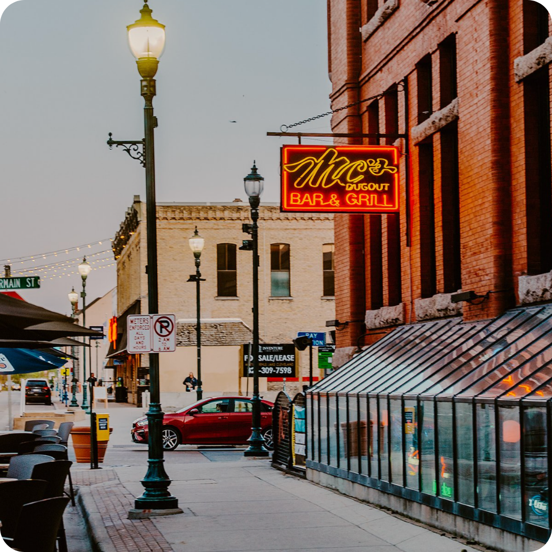 A street scene featuring an illuminated neon sign for 